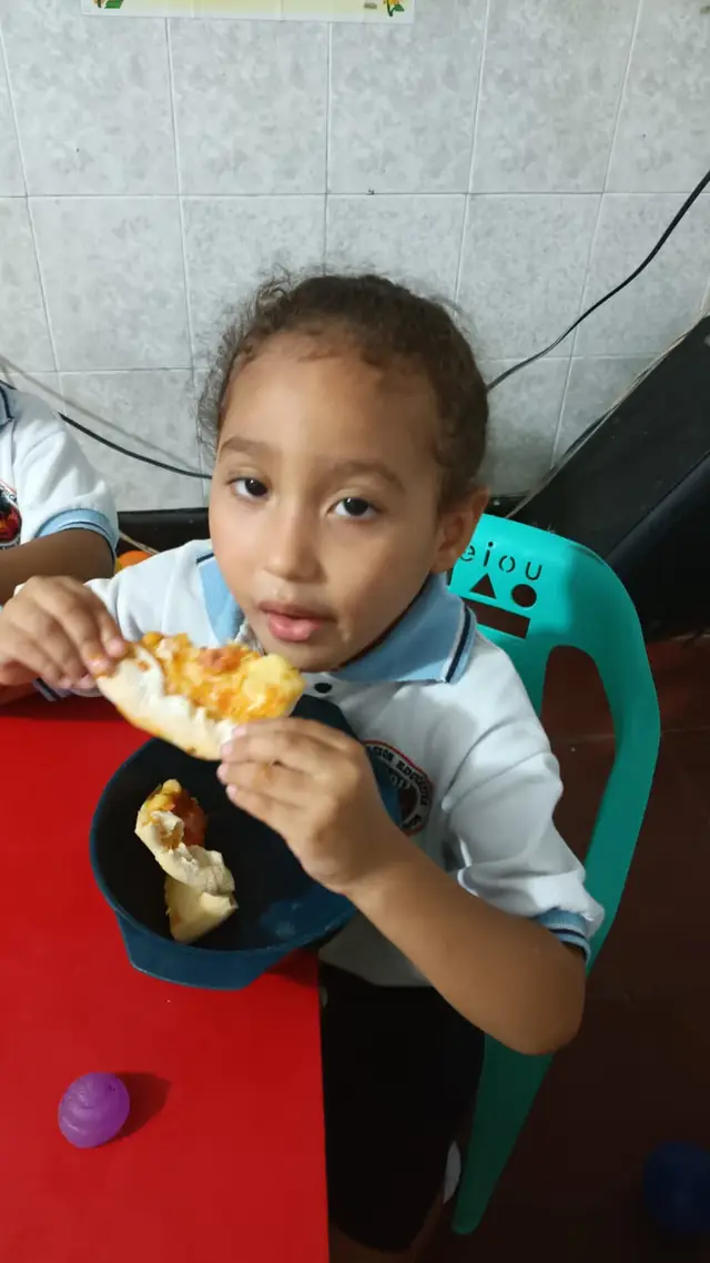 Niña comiendo pizza del emprendimiento